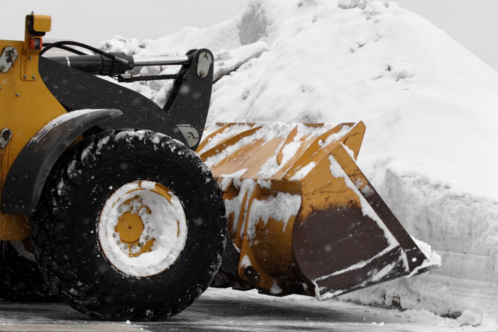 huge snow plow plowing in parking lot after storm
